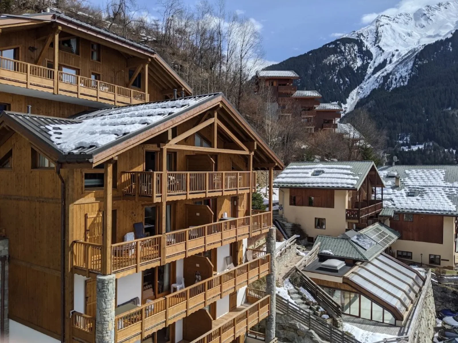 Les Balcons Étoilés wooden alpine residences with balconies facing a snow-covered mountain in Champagny